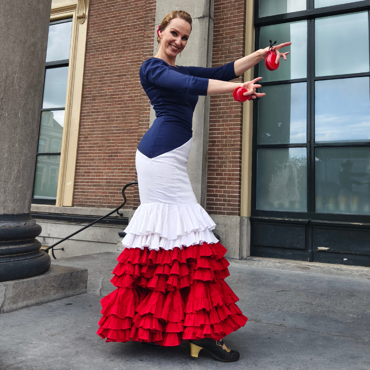 Flamenco teacher holding red castanets in a flamenco pose